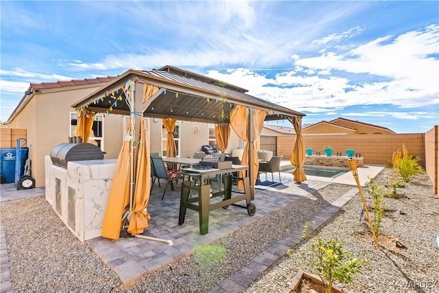 view of patio with exterior kitchen, outdoor dining area, a fenced backyard, and a gazebo