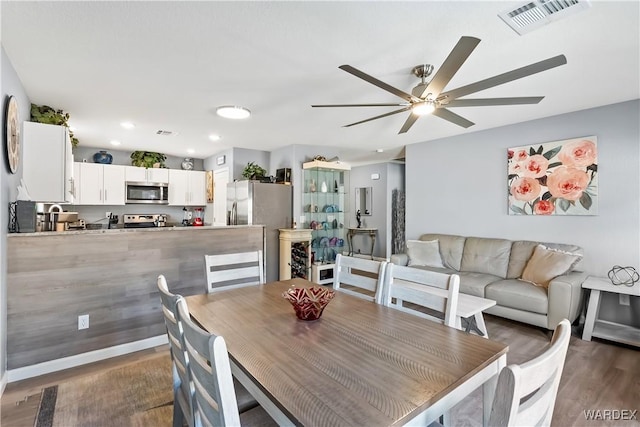 dining room with dark wood-style floors, baseboards, visible vents, and a ceiling fan