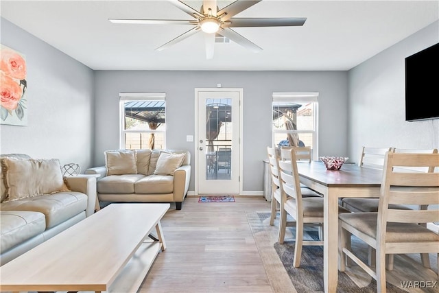 living area featuring ceiling fan, light wood-style flooring, and baseboards