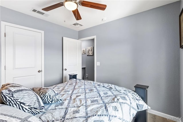 bedroom featuring ceiling fan, wood finished floors, visible vents, and baseboards