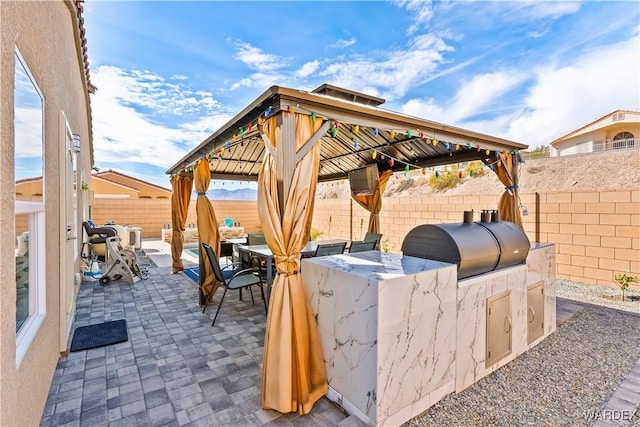 view of patio with a gazebo, exterior kitchen, area for grilling, and a fenced backyard