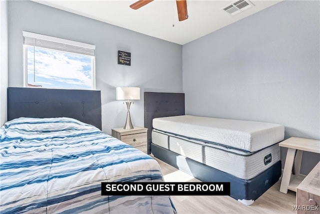 bedroom with light wood-style floors, ceiling fan, and visible vents