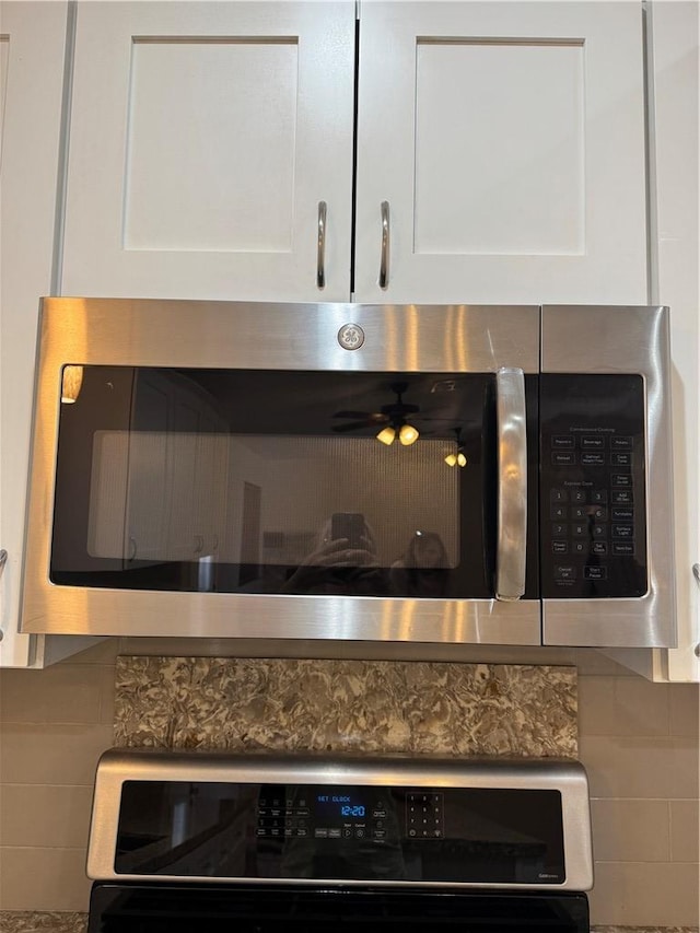 2023 E Sundance Dr, Fort Mohave, AZ 86426 - kitchen view of stainless steel microwave, decorative backsplash, and white cabinets