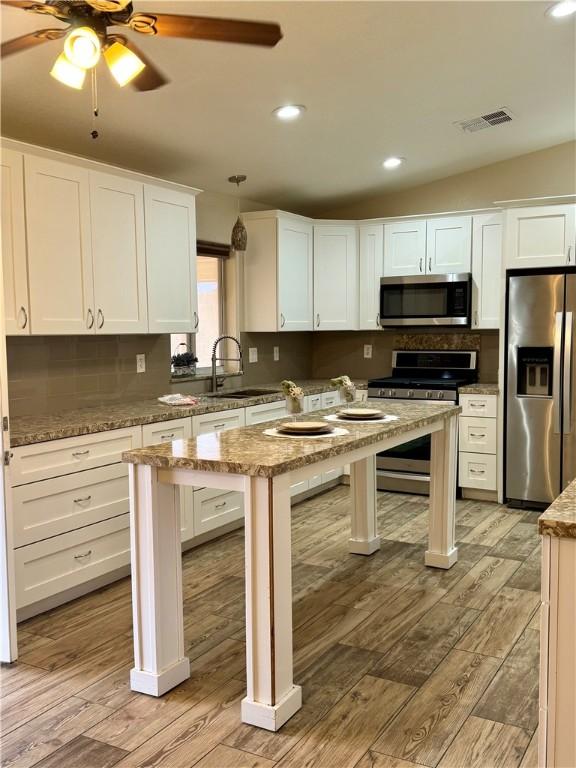 2023 E Sundance Dr, Fort Mohave, AZ 86426 - kitchen featuring stainless steel appliances, a sink, light wood-style floors, decorative backsplash, and white cabinetry