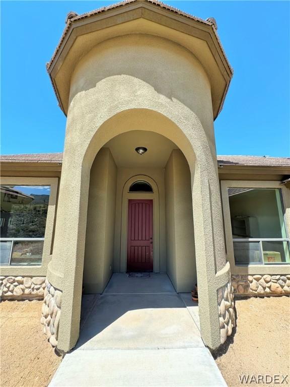 doorway to property featuring a tile roof and stucco siding