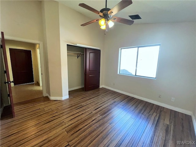 unfurnished bedroom with dark wood-style floors, a closet, and baseboards