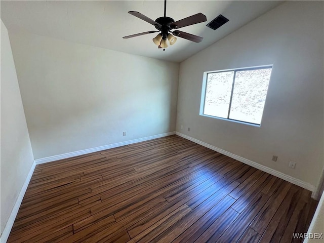 empty room featuring dark wood-type flooring, vaulted ceiling, and baseboards