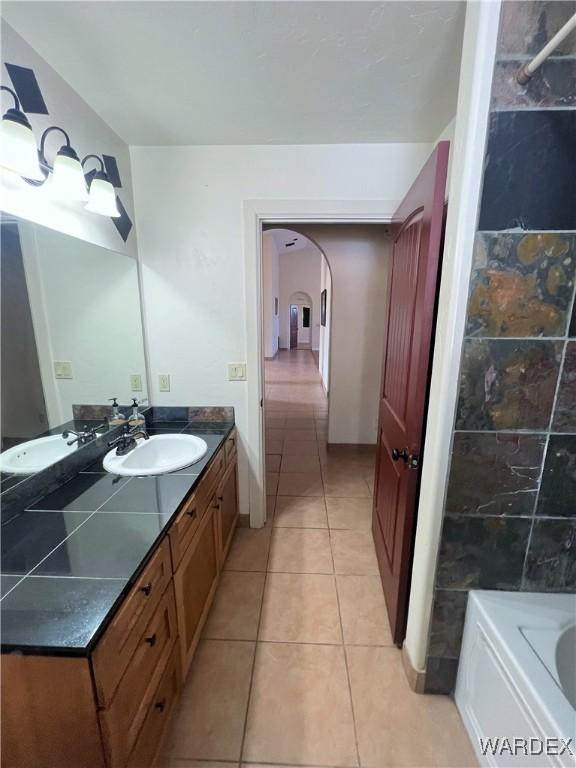 bathroom with a bath, vanity, and tile patterned floors