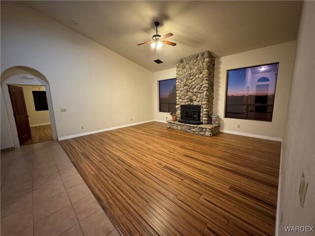 unfurnished living room featuring arched walkways, wood finished floors, a ceiling fan, and baseboards