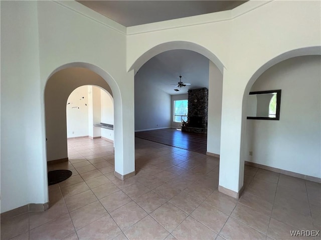 empty room with ceiling fan, light tile patterned flooring, and baseboards