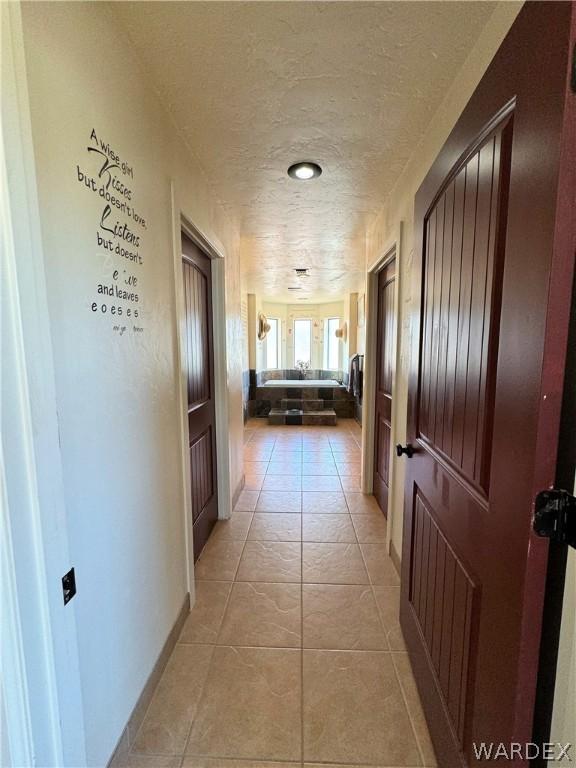 hallway with light tile patterned floors and a textured ceiling