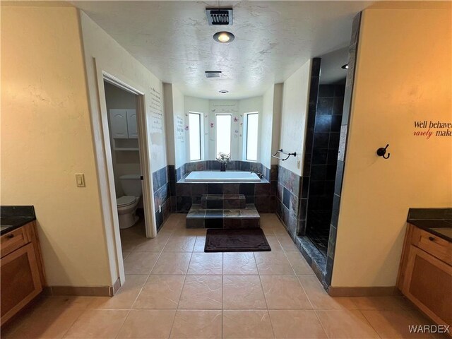 bathroom with visible vents, toilet, a garden tub, tile patterned flooring, and vanity