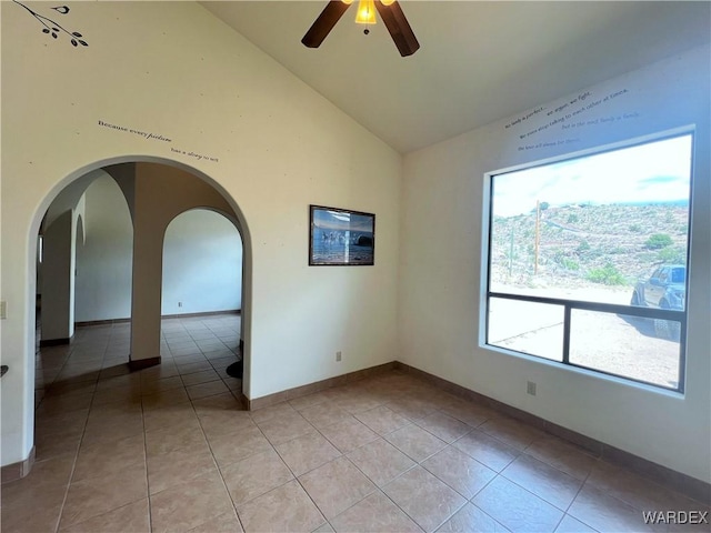 spare room featuring light tile patterned floors, ceiling fan, arched walkways, and baseboards