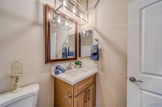 bathroom featuring a textured wall, vanity, and toilet