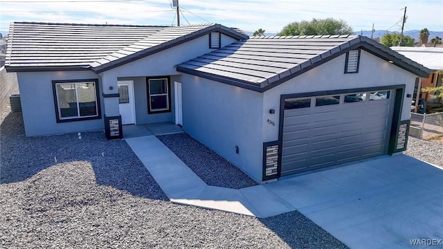 view of front of home with driveway, a tiled roof, an attached garage, and stucco siding