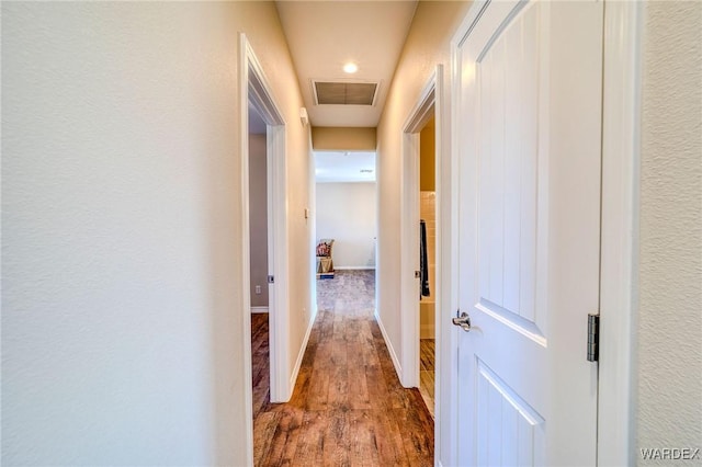 hall with baseboards, visible vents, and wood finished floors