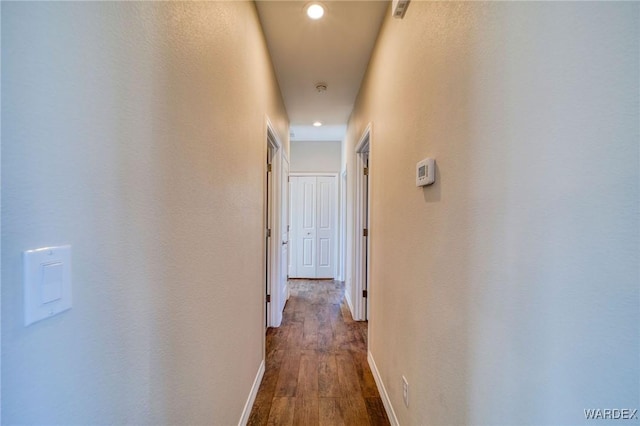 corridor featuring recessed lighting, dark wood-style flooring, and baseboards