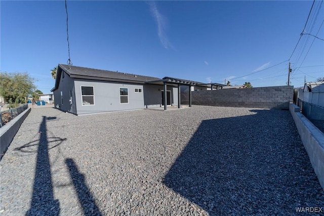 back of house featuring a fenced backyard, a patio, and stucco siding