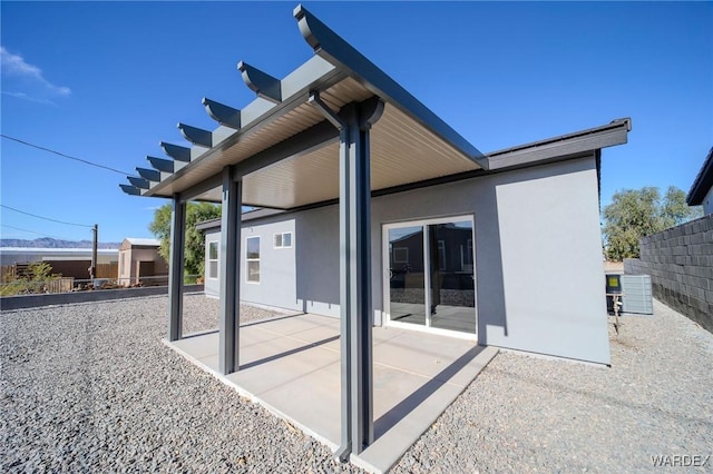 rear view of property with a patio area, fence, and stucco siding