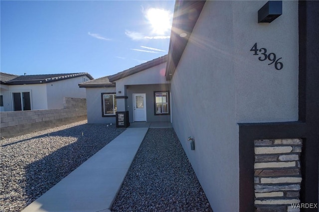 view of exterior entry featuring fence and stucco siding