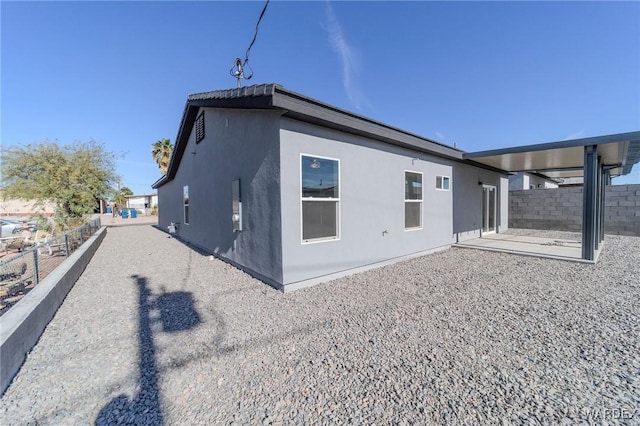 view of property exterior featuring a patio area, fence, and stucco siding