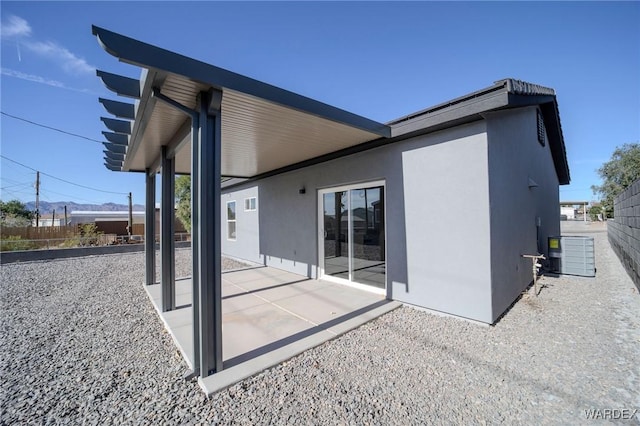 back of house featuring central AC, a patio area, fence, and stucco siding