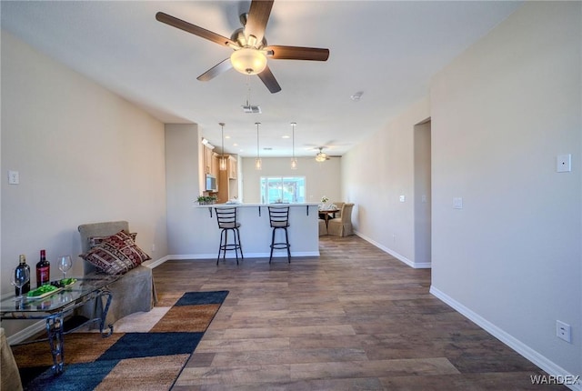 kitchen with a peninsula, dark wood-style flooring, visible vents, light countertops, and a kitchen bar