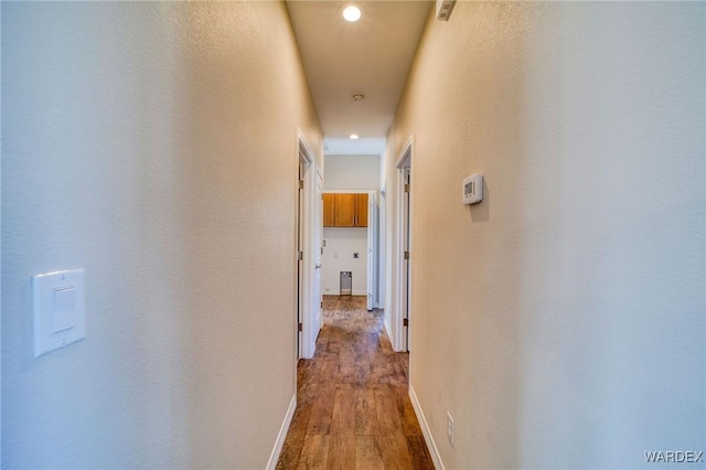 hallway featuring baseboards, wood finished floors, and recessed lighting