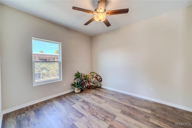 empty room with ceiling fan, baseboards, and wood finished floors