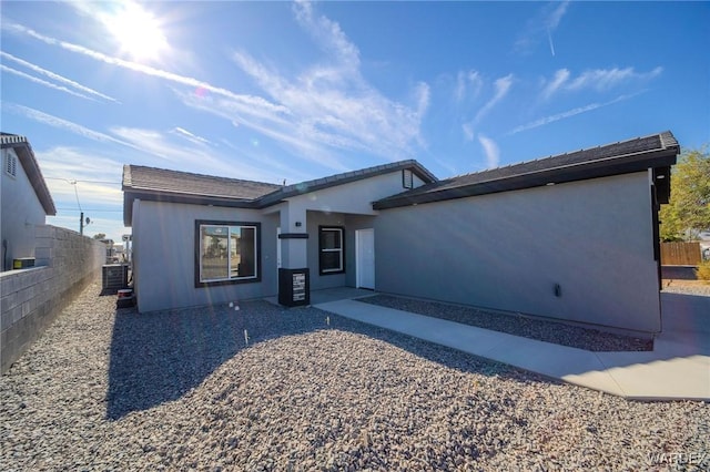 view of front of home featuring central AC, fence, and stucco siding