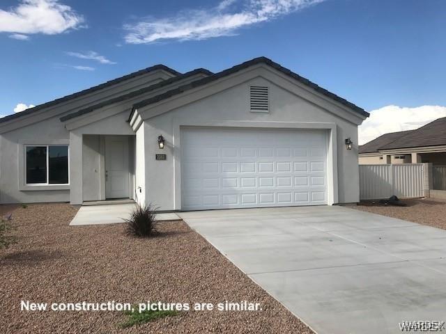 ranch-style home with a garage, concrete driveway, fence, and stucco siding