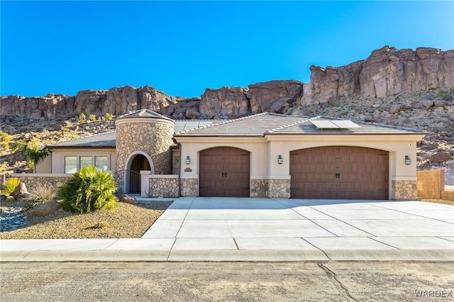 view of front facade featuring concrete driveway, stone siding, an attached garage, a mountain view, and stucco siding