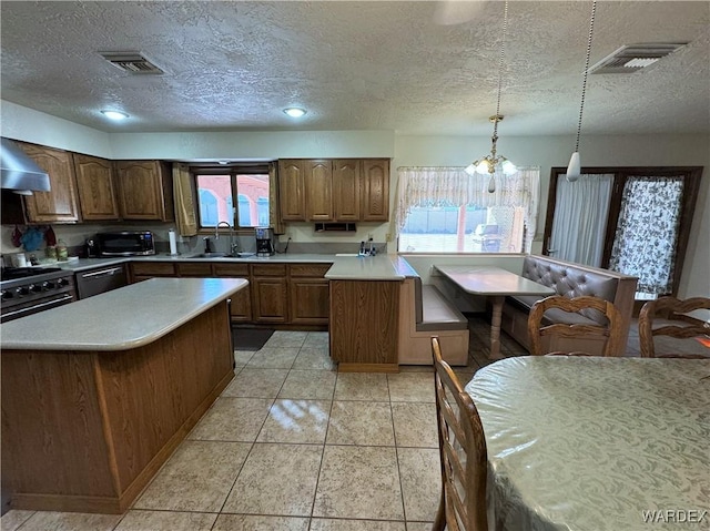 kitchen featuring visible vents, stainless steel range, light countertops, and a sink