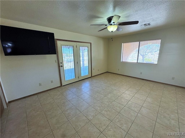 unfurnished room with a ceiling fan, visible vents, a textured ceiling, and baseboards