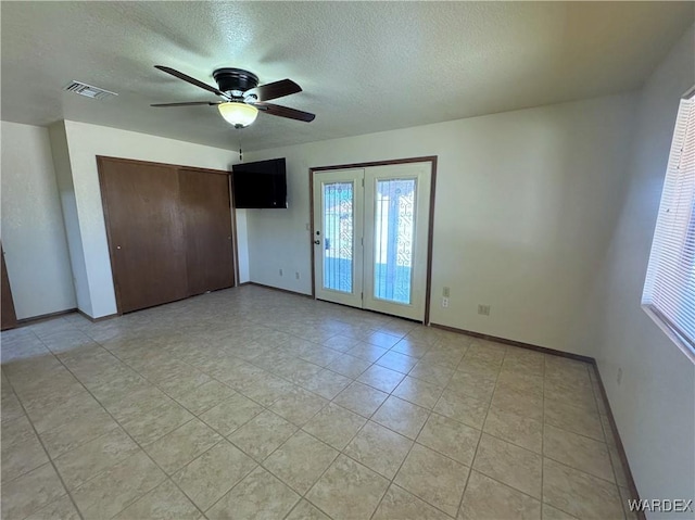 unfurnished bedroom with a textured ceiling, a ceiling fan, visible vents, baseboards, and a closet