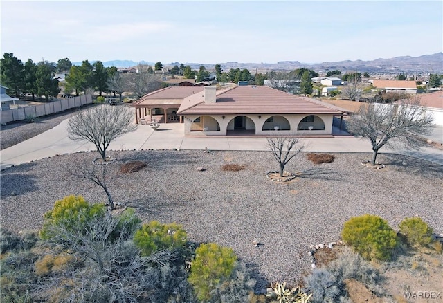 view of front facade with a patio area, a mountain view, a tiled roof, and fence