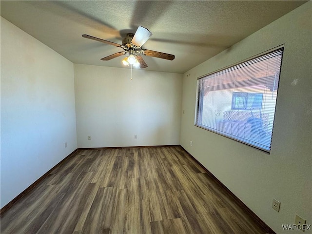 spare room featuring a textured ceiling, wood finished floors, a ceiling fan, and baseboards