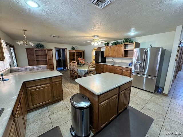 kitchen featuring visible vents, brown cabinetry, stainless steel fridge with ice dispenser, light countertops, and open shelves