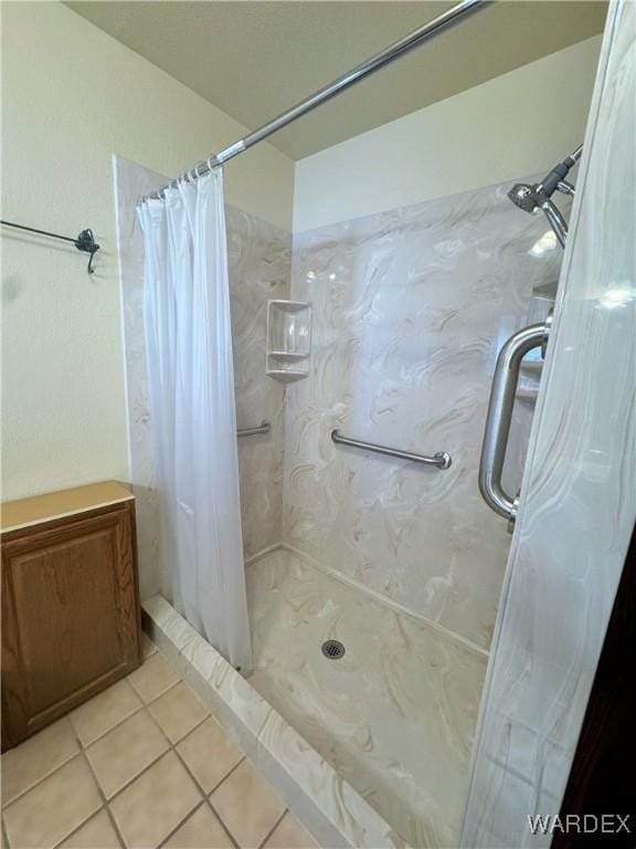 full bathroom with tile patterned flooring and a shower stall