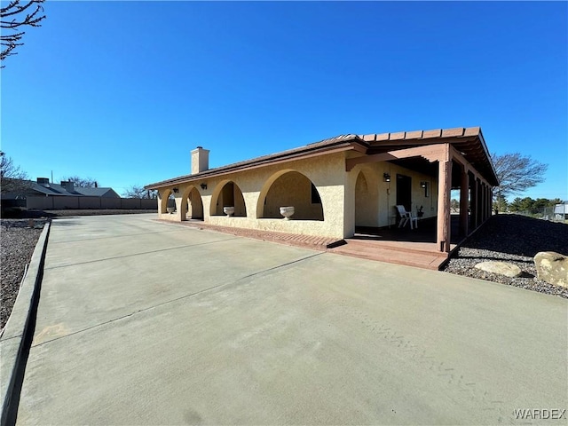 view of front of house with fence, a patio, and stucco siding