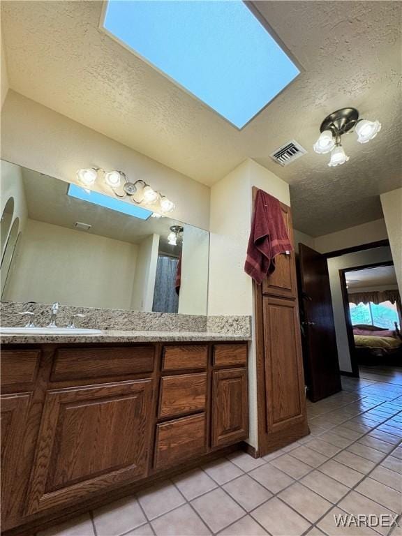 bathroom featuring a textured ceiling, vanity, tile patterned flooring, and visible vents