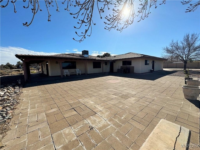 rear view of house featuring a patio area, fence, and stucco siding