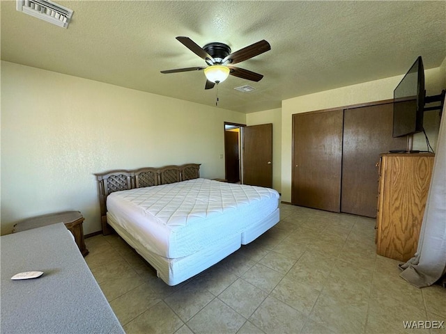 bedroom with a textured ceiling, ceiling fan, a closet, and visible vents