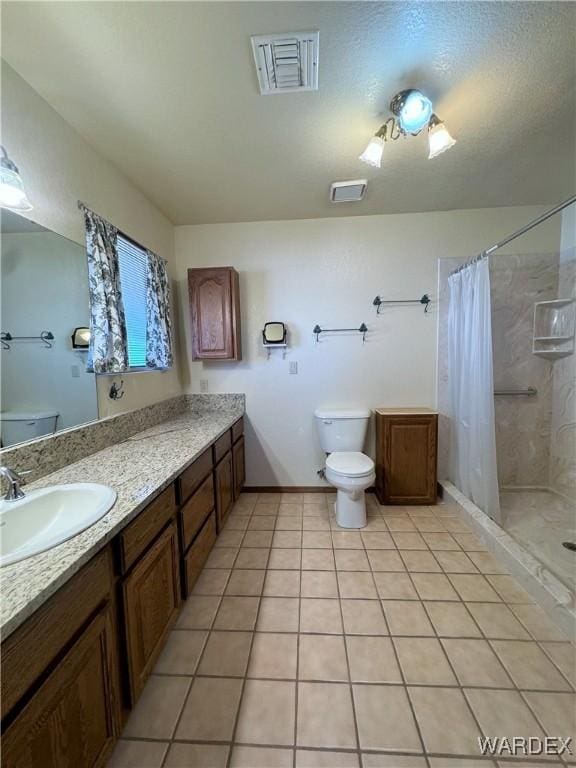 bathroom featuring toilet, vanity, visible vents, a tile shower, and tile patterned floors