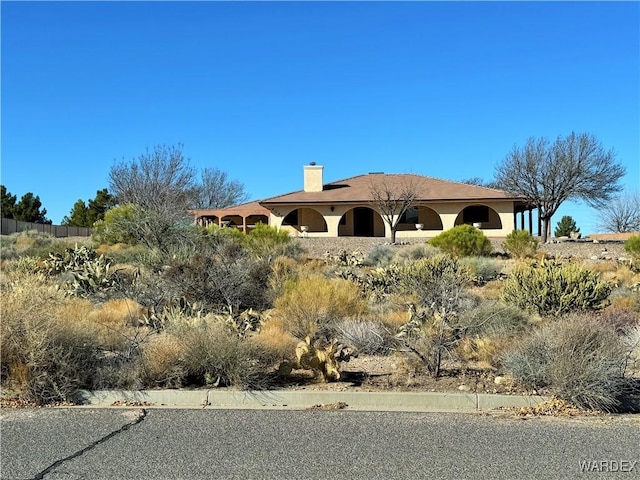 view of front facade with a chimney and stucco siding