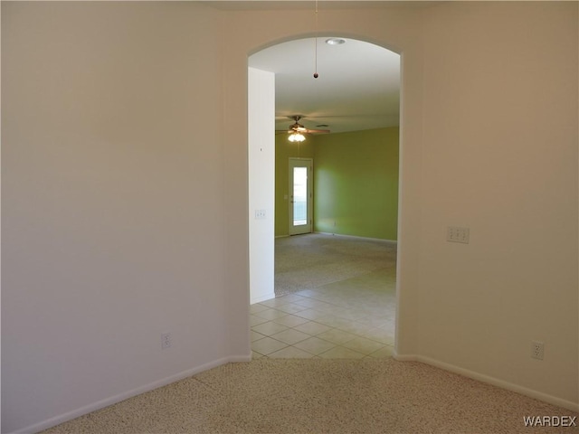 2353 Halfmoon Way, Bullhead City, AZ 86442 - empty room featuring arched walkways, baseboards, light colored carpet, and light tile patterned floors