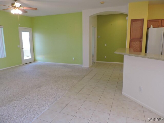 2353 Halfmoon Way, Bullhead City, AZ 86442 - unfurnished room featuring light tile patterned flooring, baseboards, ceiling fan, light colored carpet, and arched walkways
