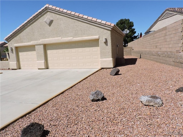 2353 Halfmoon Way, Bullhead City, AZ 86442 - view of home's exterior featuring a garage, fence, stucco siding, and driveway