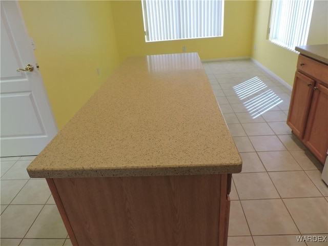 2353 Halfmoon Way, Bullhead City, AZ 86442 - kitchen featuring light tile patterned floors, light stone countertops, a kitchen island, and brown cabinets