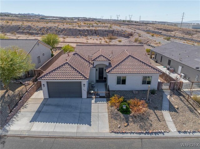 view of front of house featuring a garage, fence, a tile roof, concrete driveway, and stucco siding